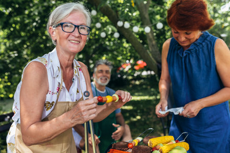 Elderly people are making barbeque, drinking beverages, making memories, and laughing.の写真素材