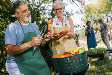 Elderly people are making barbeque, drinking beverages, making memories, and laughing.の写真素材