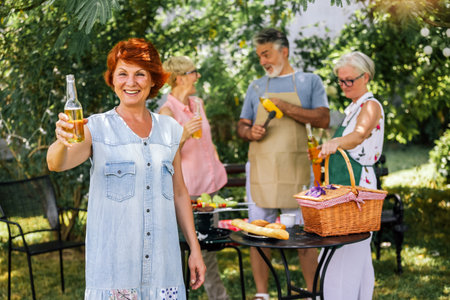 Elderly people are making barbeque, drinking beverages, making memories, and laughing.の写真素材