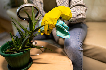 Young blonde woman taking care of her plants. Using magnifying glass