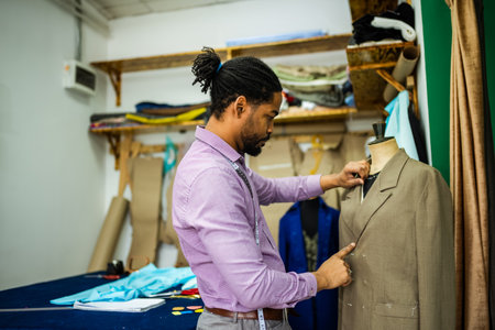 Male African American tailor measuring the suit with measuring tape.の写真素材