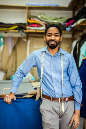 Young African American tailor smiling in his own atelier.
