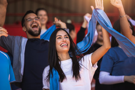 Football / soccer fans are cheering for their team at the stadium on the matchの写真素材