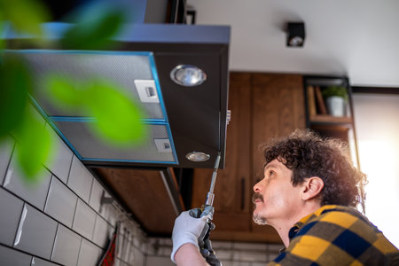 Latino man fixing aspirator in the kitchen.の写真素材