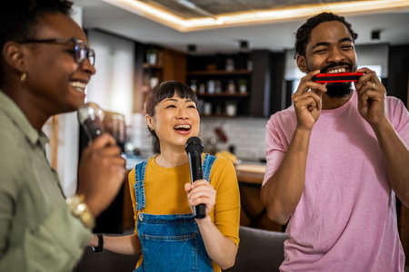 Multiracial group of friends having karaoke night. Singing in to the microphone, drinking beer and playing mouth organ.の写真素材