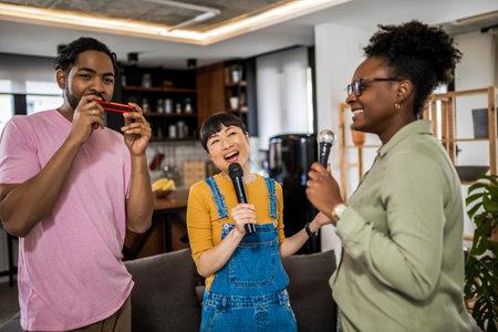 Multiracial group of friends having karaoke night. Singing in to the microphone, drinking beer and playing mouth organ.の写真素材