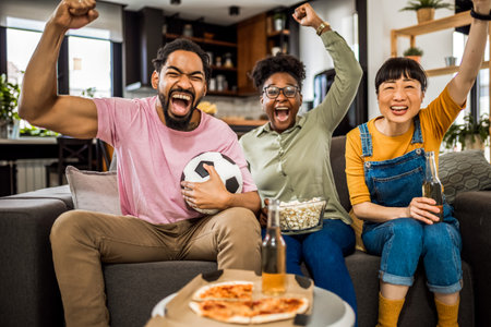 Multiracial group of friends watching soccer game, cheering , eating pizza and drinking beer.の写真素材