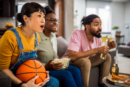 Multiracial group of friends watching basketball game, eating pizza, drinking beer and cheering.の写真素材