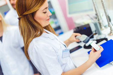 Pharmacist scanning price on a medicine box with barcode reader in pharmacy store.の写真素材