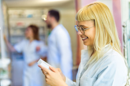 Young blonde smiling pharmacist searching for medication in the pharmacy.の写真素材