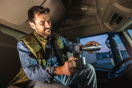 Young handsome man driving long vehicle and drinking coffee so he could get some energy.
