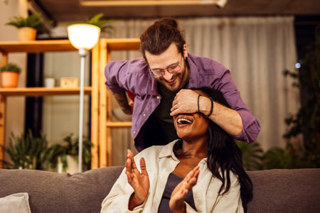 Loving boyfriend surprising his African American girlfriend with a gift.