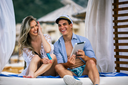 Young beautiful couple ordering online with the card, on the beach. Boyfriend wearing sailor cap.の写真素材