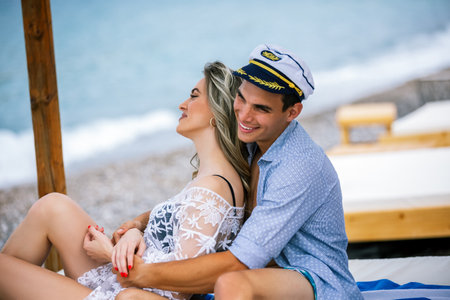 Beautiful young couple having good time on the beach. Boyfriend is wearing sailor cap.の写真素材