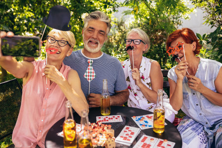 Elderly people are making themselves young again and coming out of their comfort zone using silly glasses, hats, and mustaches.They are also drinking their favourite beverages and making great memoriesの写真素材