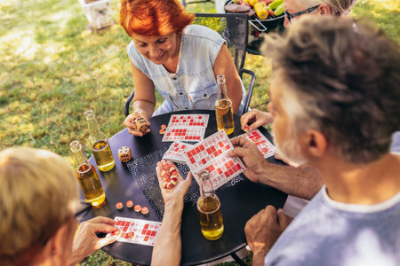 Group of elderly retired people playing bingo outside. Drinking beer and enjoying some time outside.の写真素材