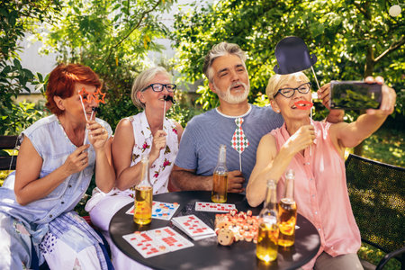 Elderly people are making themselves young again and coming out of their comfort zone using silly glasses, hats, and mustaches.They are also drinking their favourite beverages and making great memoriesの写真素材