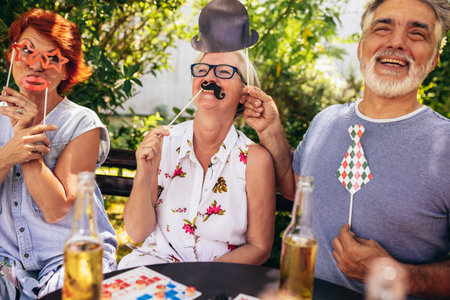 Elderly people are making themselves young again and coming out of their comfort zone using silly glasses, hats, and mustaches.They are also drinking their favourite beverages and making great memoriesの写真素材