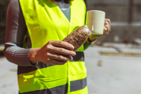 Three constructions workers having coffee and lunch break at construction site.の写真素材