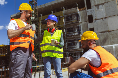 Three constructions workers having coffee and lunch break at construction site.の写真素材
