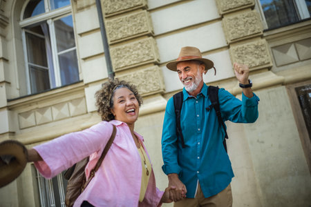 Elderly married couple standing happy in the city center. Throwing hats in the air.の写真素材