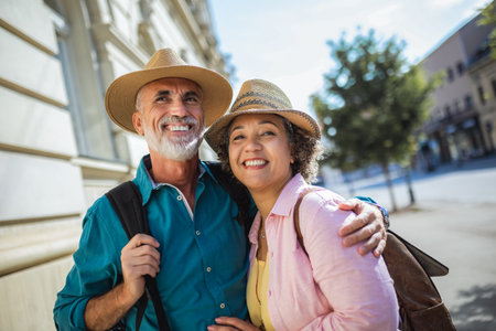 Elderly married couple exploring new city. They are wearing hats and backpacks.の写真素材