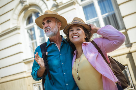 Elderly married couple exploring new city. They are wearing hats and backpacks.の写真素材