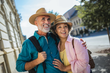 Elderly married couple exploring new city. They are wearing hats and backpacks.の写真素材