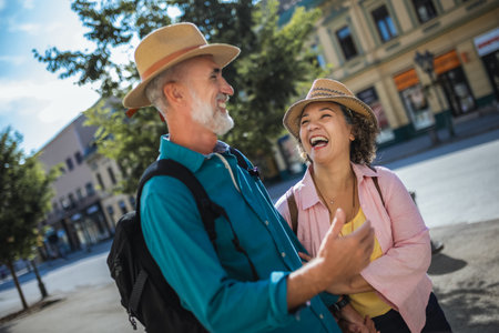 Elderly married couple exploring new city. They are wearing hats and backpacks.の写真素材