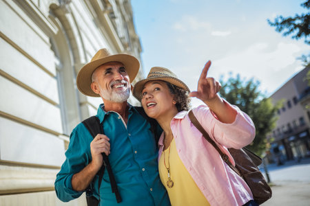 Elderly married couple exploring new city. They are wearing hats and backpacks.の写真素材