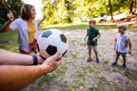Family of four playing soccer in the park.の写真素材
