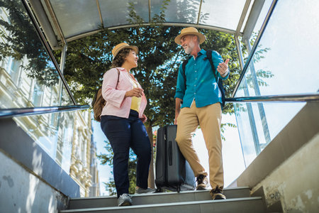 Old married couple walking down the stairs, entering metro with luggage.の写真素材