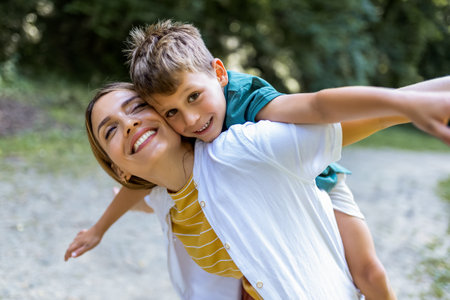 Young beautiful mother playing with her son piggy back.の写真素材