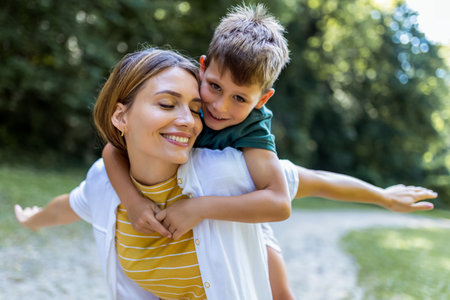 Young beautiful mother playing with her son piggy back.の写真素材