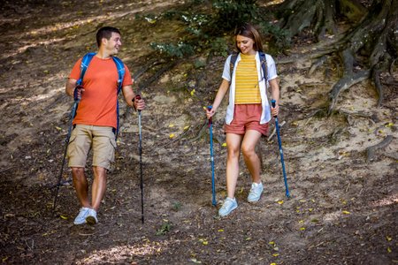 Couple hiking in the forest with hiking poles.の写真素材