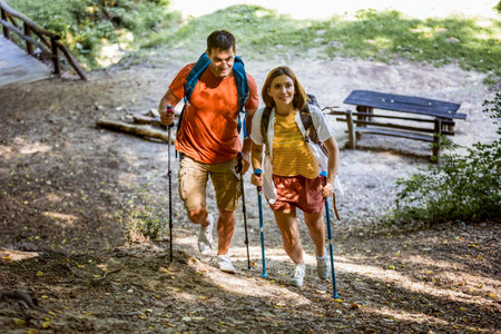 Married couple hiking in a forest with hiking poles and other  hiking equipment.の写真素材