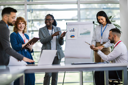 Two businesswoman talking on a meeting in an office with other colleagues. Showing graphics, diagrams and statistics.の写真素材