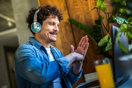 Happy Hispanic deaf man talking in deaf language on a video call on his laptop.の写真素材