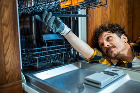 Latino man fixing dishwasher in the kitchen.の写真素材