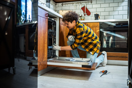 Latino man fixing dishwasher in the kitchen.の写真素材