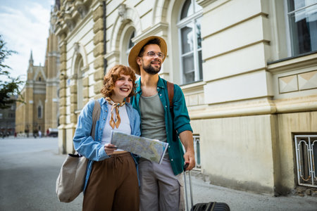 Young couple on a vacation exploring the city. Using the map so they dont get lost. Having suitcases with them.の写真素材