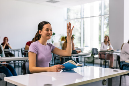 Female student raising her hand in class to ask some question.の写真素材