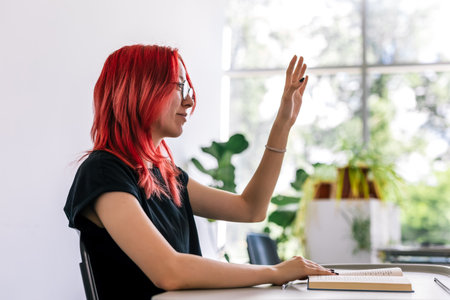 Red head female student raising her hand in class to ask some question.