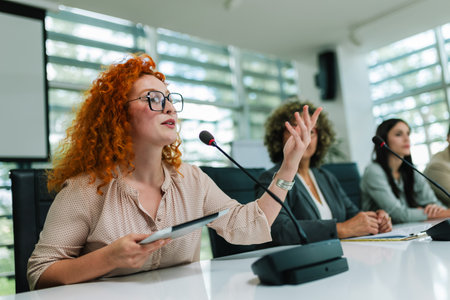 Ginger woman CEO talking on the microphone on meeting with her colleagues about business plan, future collaboration.の写真素材