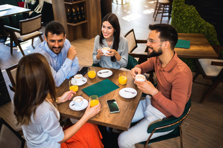 Group of friends laughing together at the coffee shop. They drink orange juice and hang out together.の写真素材