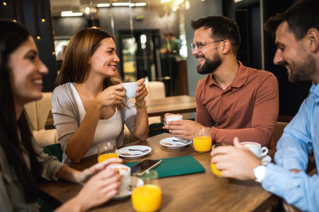 Group of friends met at the cafe. Drinking coffee and orange juice. Girl and guy are talking while the other friends are listening to them.の写真素材
