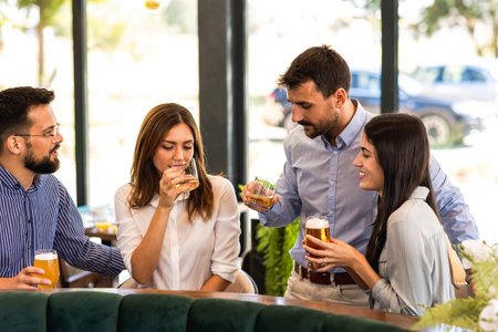 Group of friends hanging out in restaurant and drinking beer. Having fun, talking and making memories.の写真素材