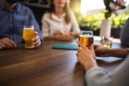 Group of friends hanging out in restaurant and drinking beer. Having fun, talking and making memories.の写真素材