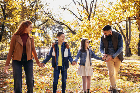Happy family walking in the park on a sunny fall day. Colorful park.の写真素材