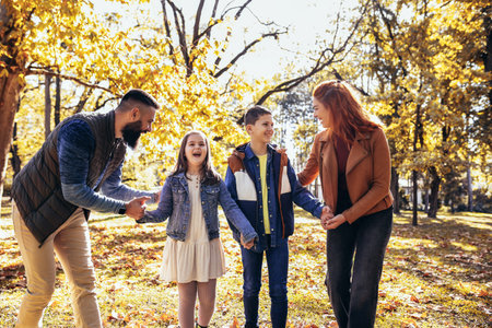 Happy family walking in the park on a sunny fall day. Colorful park.の写真素材